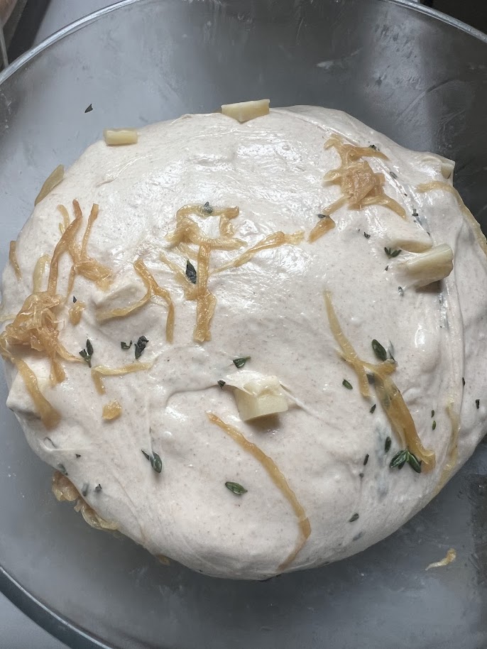 Onions, cheese, and thyme on top of the dough, ready for the first fold