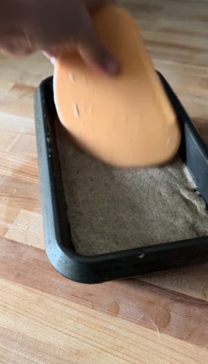 Into the oiled pan with a wet scraper